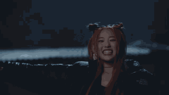 a woman with red hair is wearing a black jacket that says the north face