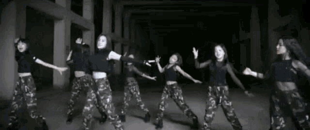 a group of girls are dancing together in a dark room .