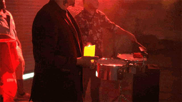 a man in a suit is holding a yellow candle