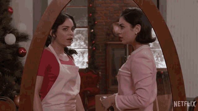 two women standing in front of a mirror with a netflix logo on the bottom