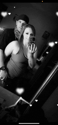 a black and white photo of a man and woman taking a selfie in front of a mirror