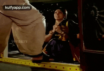 a woman is sitting on the steps of a bus while a man stands next to her .