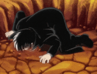 a man in a black suit is kneeling down on a rocky ground