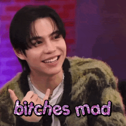 a young man is smiling and giving a thumbs up with the words `` bitches mad '' .