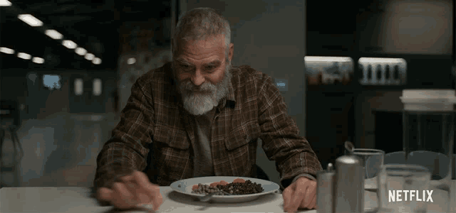 a man sitting at a table with a plate of food and a netflix logo on the bottom