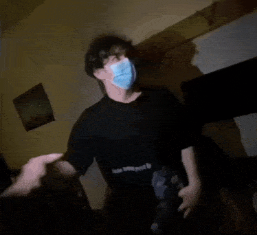 a man wearing a blue mask is standing in a dark room .