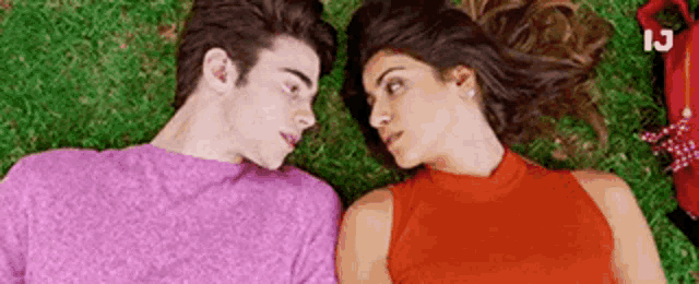 a man and a woman are laying on top of each other on the grass .