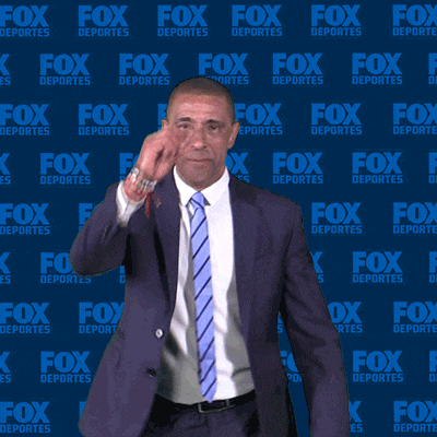 a man in a suit and tie is standing in front of a fox deportes wall