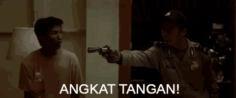a man is pointing a gun at another man with the words angkat tangan behind him .