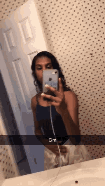 a woman taking a picture of herself in a bathroom mirror with gm written on the bottom right