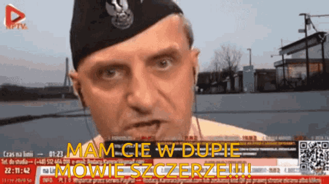 a man wearing a hat and ear buds is on a tv screen with the words " mam cie w dupie "