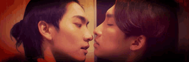 two men are kissing each other in front of a wall