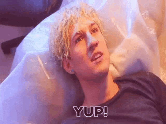 a young man with blonde hair is laying in a plastic bag .