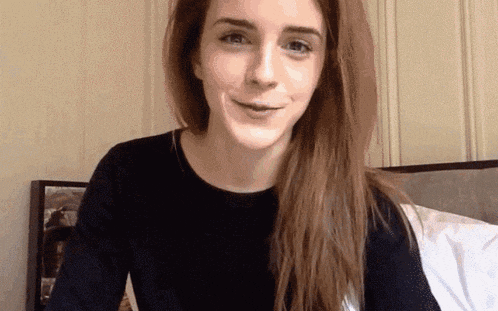 a woman with long hair is sitting in front of a bed