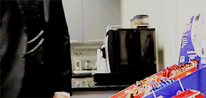 a man in a suit and tie is standing in front of a box of candy