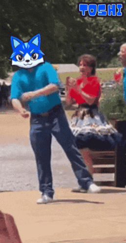 a man in a blue shirt with a blue cat mask on his face is dancing in front of a sign that says " toshi "