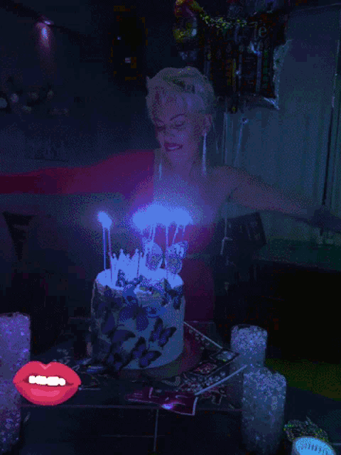 a woman in a red dress lighting candles on a birthday cake