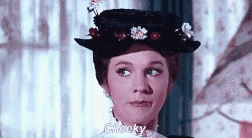 a woman wearing a hat with cherries on it is making a funny face .