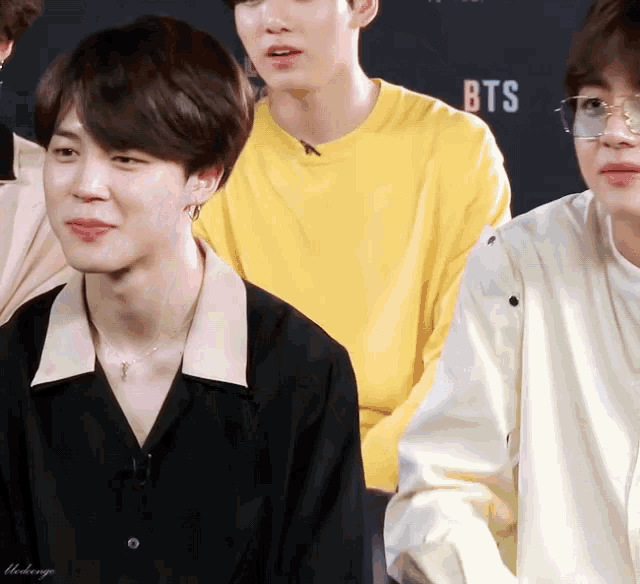a group of young men are sitting in front of a sign that says ' bts ' on it