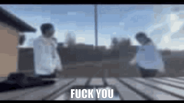 a blurry picture of two people standing next to each other with the words `` fuck you '' written in the corner .