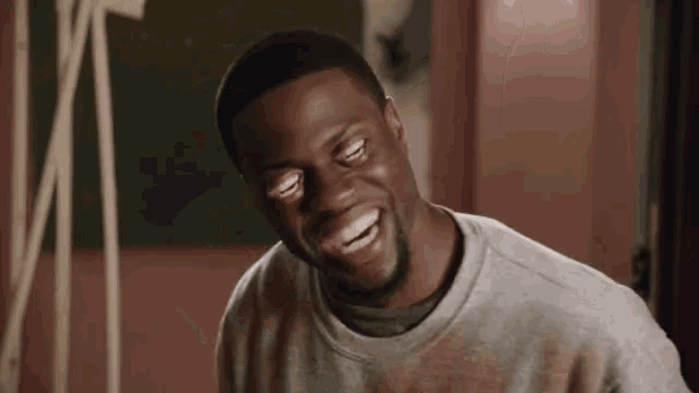 a man is laughing with his eyes closed and his mouth open in a room .