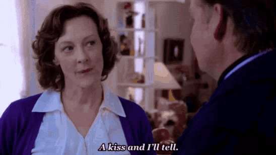 a woman in a purple sweater says a kiss and i 'll tell .