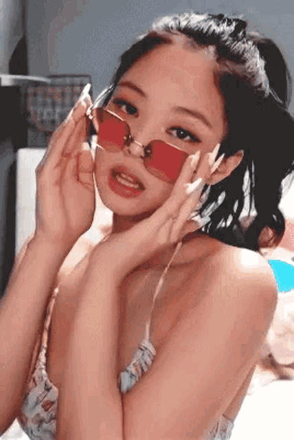 a woman wearing red sunglasses and a ponytail is looking at the camera .