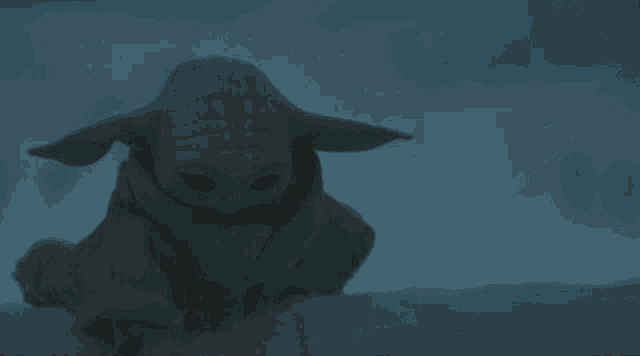 a baby yoda crawling in the snow with a hand pointing at him