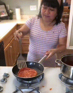 a woman in a striped shirt is stirring a frying pan with a spatula