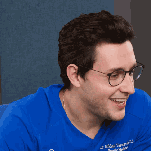 a man wearing glasses and a blue shirt that says mikhail varshansky