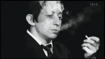 a black and white photo of a man smoking a cigarette .