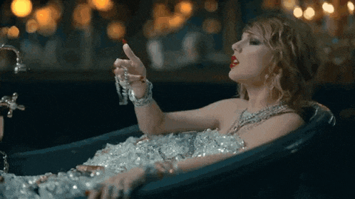 a woman is laying in a bathtub covered in ice and holding a lipstick .