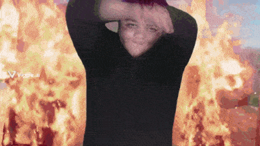 a man in a black hoodie is standing in front of a fire with a viggle.ai logo