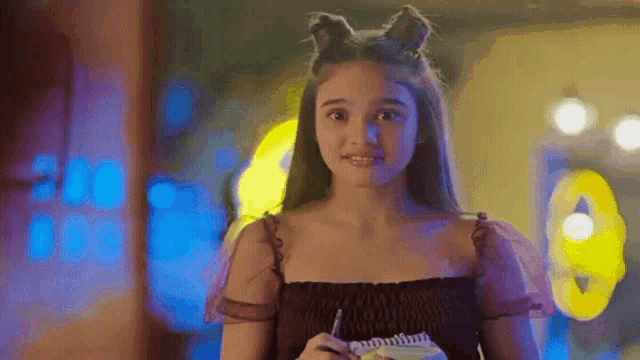 a girl with cat ears on her head is holding a notebook .