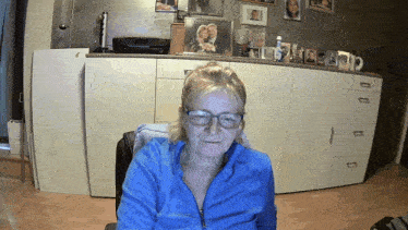 a woman wearing glasses is sitting in front of a dresser