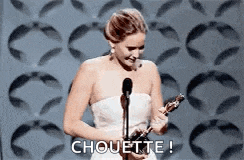 a woman in a white dress is holding an oscar trophy and smiling .