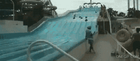 a water slide at a water park with people riding it .
