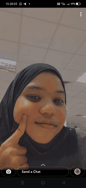 a girl in a black hijab is making a funny face and the time is 15:27:03