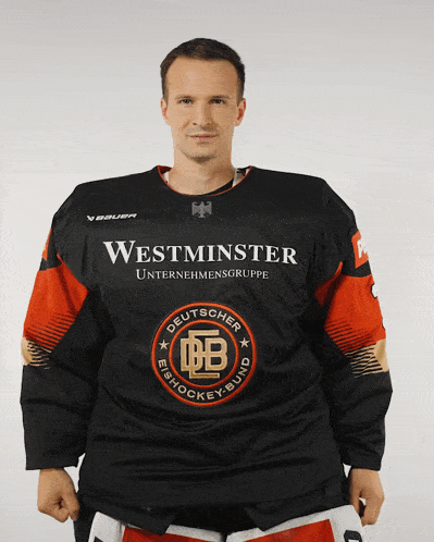 a man wearing a black and orange westminster unternehmensgruppe jersey