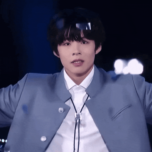 a young man wearing a blue jacket and white shirt with a black tie