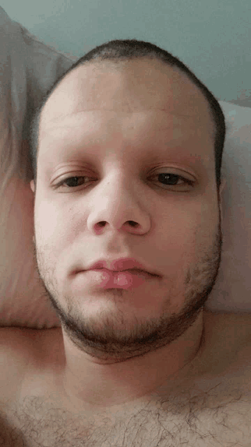a man with a shaved head and a beard looks at the camera