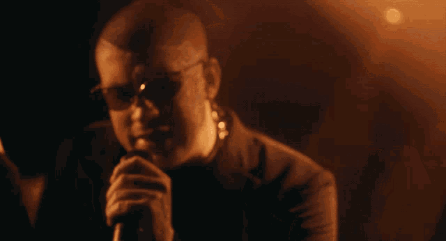 a man singing into a microphone with sunglasses on