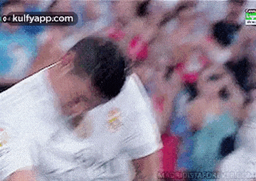 a soccer player is being tackled by another player in a crowd .