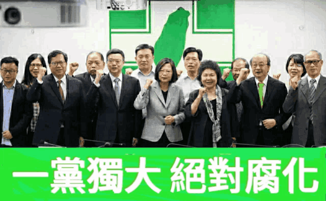 a group of people standing in front of a green sign with chinese writing