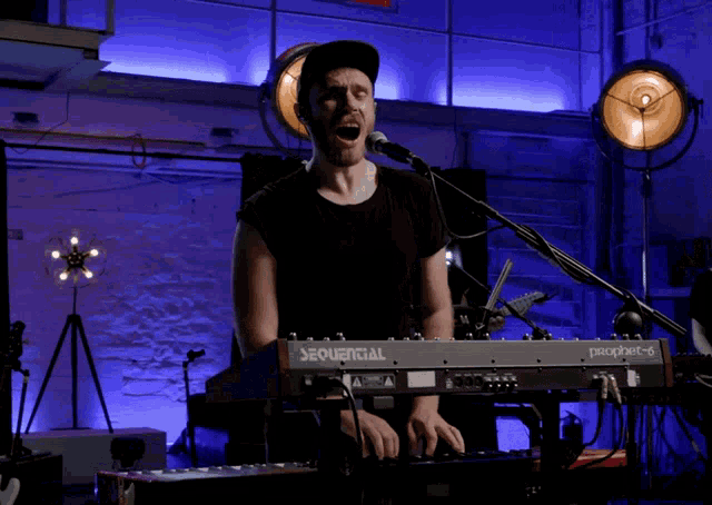 a man singing into a microphone while playing a keyboard that says sequential