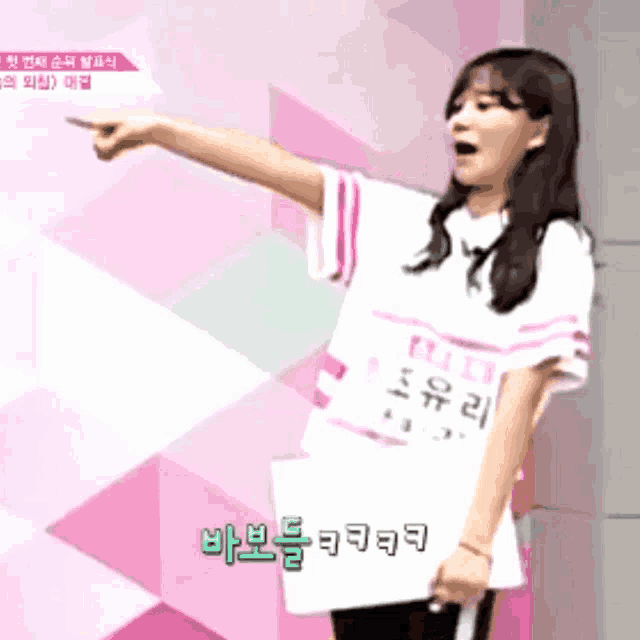 a girl wearing a shirt that says ' nct ' on it is pointing at something