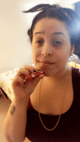 a woman with a tattoo on her wrist is smoking a red cigarette