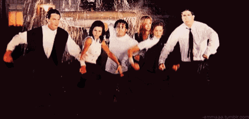 a group of people are standing in front of a fountain .