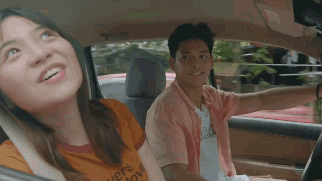 a man and a woman are in a car and the woman is wearing a shirt that says " i love you "