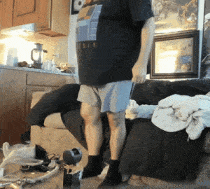 a man wearing a holy t-shirt is standing on a messy couch